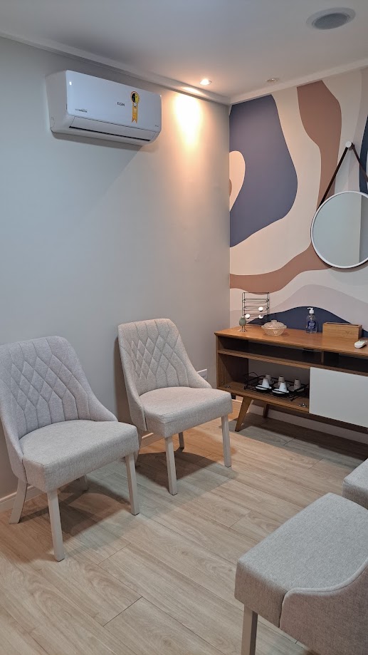 Sala de espera com poltronas claras e mural artístico